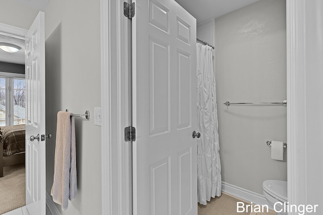 bathroom featuring toilet, baseboards, tile patterned floors, and a shower with curtain
