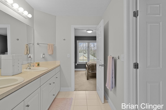 ensuite bathroom with double vanity, a sink, baseboards, tile patterned floors, and connected bathroom