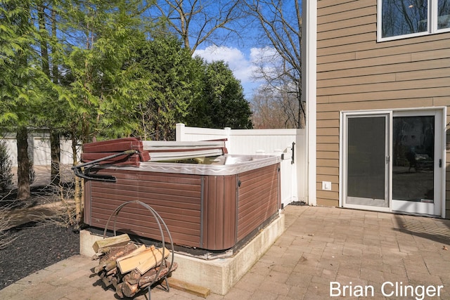 view of patio / terrace featuring a hot tub and fence