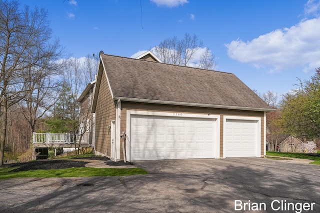 view of home's exterior with roof with shingles and aphalt driveway