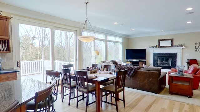dining space with crown molding, recessed lighting, a high end fireplace, and light wood-type flooring