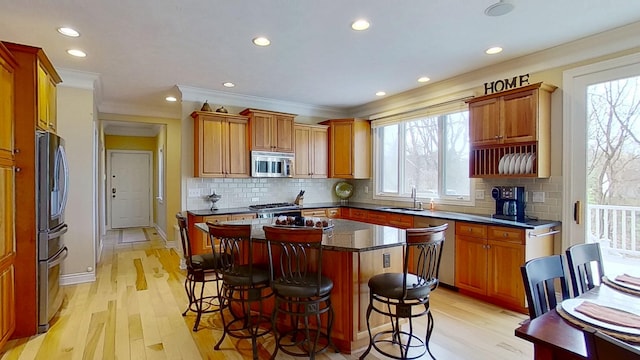 kitchen featuring appliances with stainless steel finishes, a breakfast bar, tasteful backsplash, and light wood-type flooring