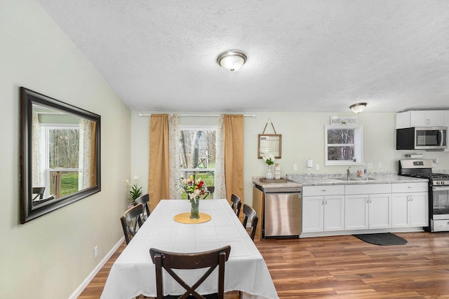 dining space with baseboards, a textured ceiling, and wood finished floors