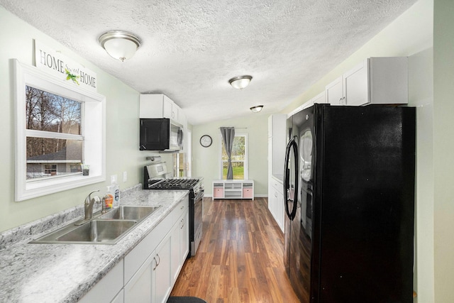 kitchen with freestanding refrigerator, dark wood-style flooring, white cabinets, stainless steel range with gas stovetop, and a sink