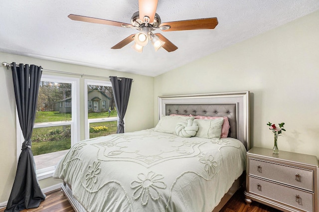 bedroom with a textured ceiling, dark wood finished floors, ceiling fan, and vaulted ceiling