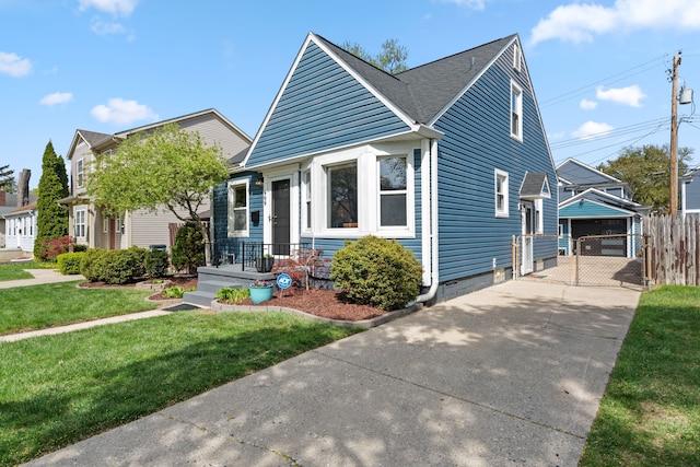 bungalow-style house with fence, a front yard, a gate, concrete driveway, and a detached garage