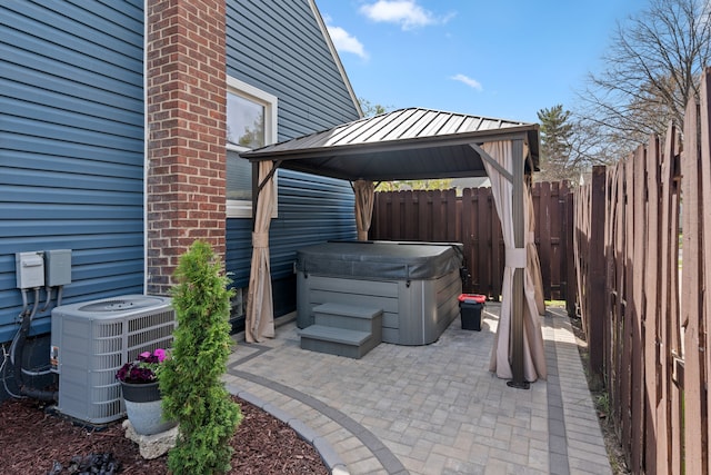 view of patio featuring a gazebo, a hot tub, central air condition unit, and fence