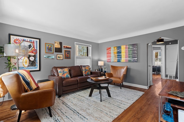 living room with arched walkways, baseboards, visible vents, and wood finished floors