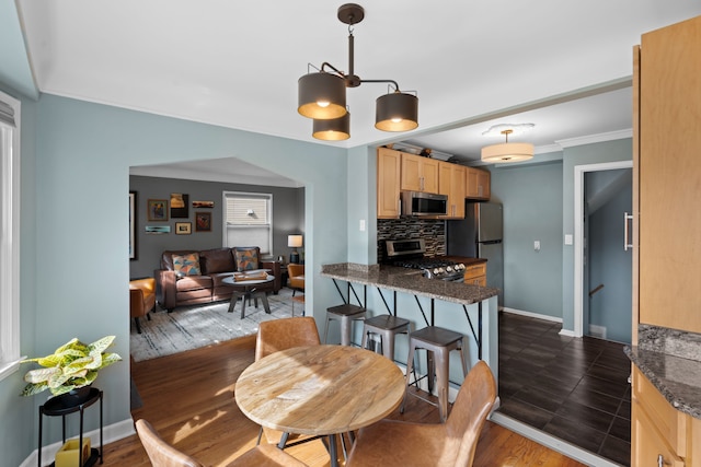 dining space featuring baseboards, dark wood finished floors, and ornamental molding