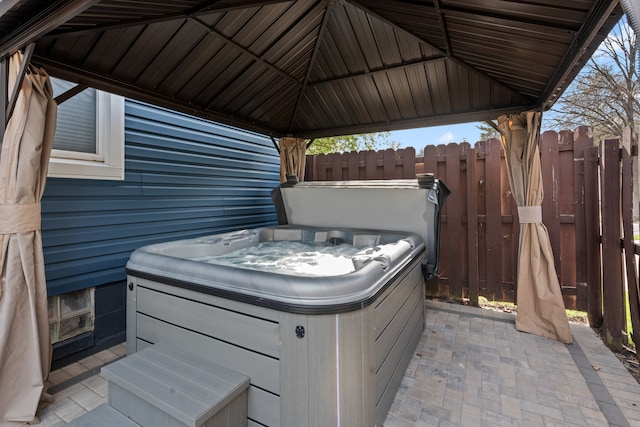 view of patio / terrace with a hot tub and fence