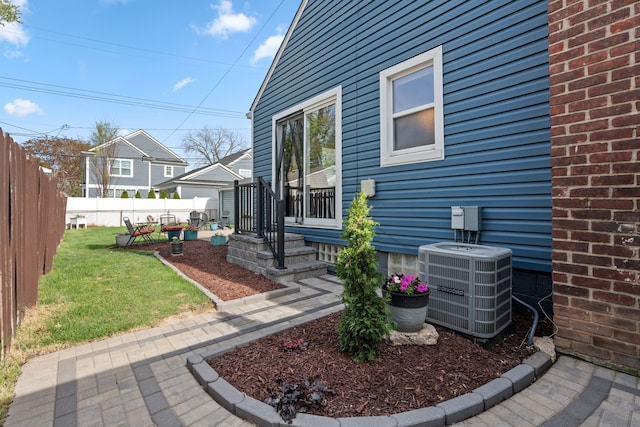 view of home's exterior featuring central air condition unit, a lawn, and fence