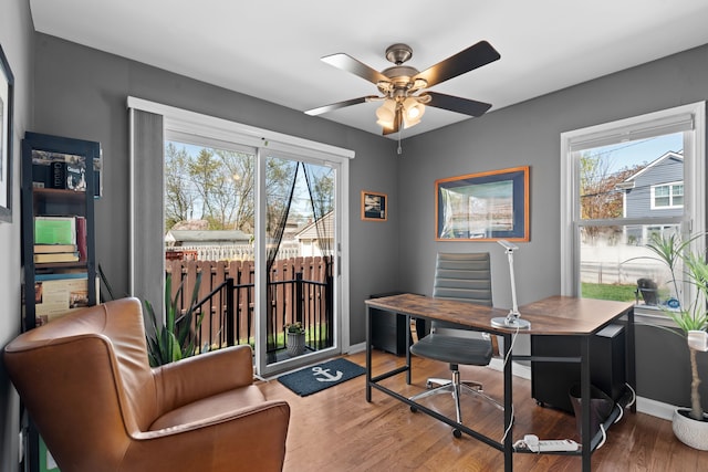 office featuring baseboards, ceiling fan, plenty of natural light, and wood finished floors