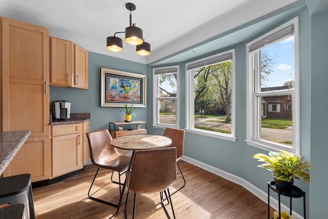 dining area with baseboards, light wood-style flooring, and a notable chandelier