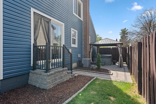 exterior space featuring a hot tub, a patio, fence, and central air condition unit