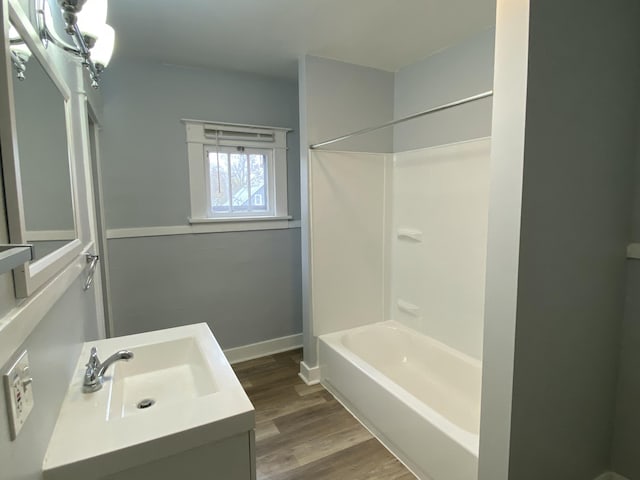 bathroom with vanity, shower / bathtub combination, baseboards, and wood finished floors