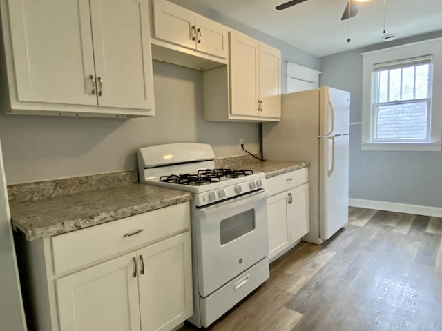 kitchen featuring white appliances, a ceiling fan, baseboards, white cabinetry, and wood finished floors