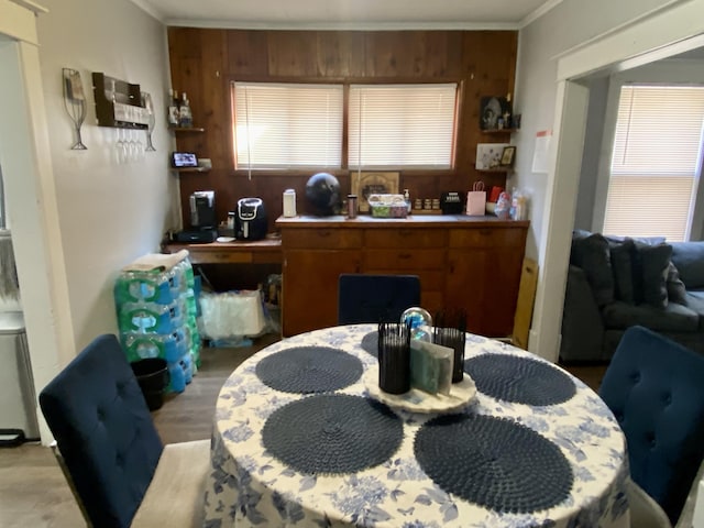 dining area featuring crown molding, light wood-style floors, and wood walls