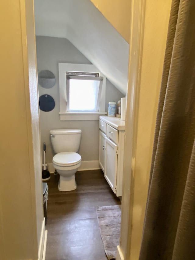 full bathroom with vanity, wood finished floors, vaulted ceiling, and toilet