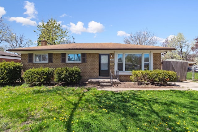 single story home with fence, a chimney, a front yard, and brick siding