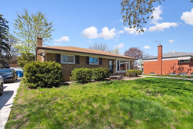 single story home with a chimney, brick siding, and a front yard