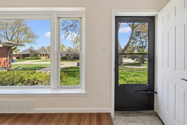 doorway with baseboards, visible vents, and wood finished floors