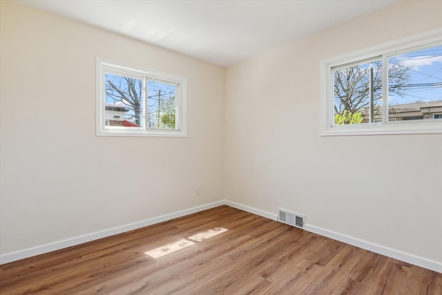 unfurnished room with baseboards, light wood finished floors, and visible vents