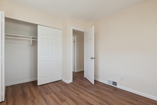 unfurnished bedroom with visible vents, baseboards, wood finished floors, and a closet