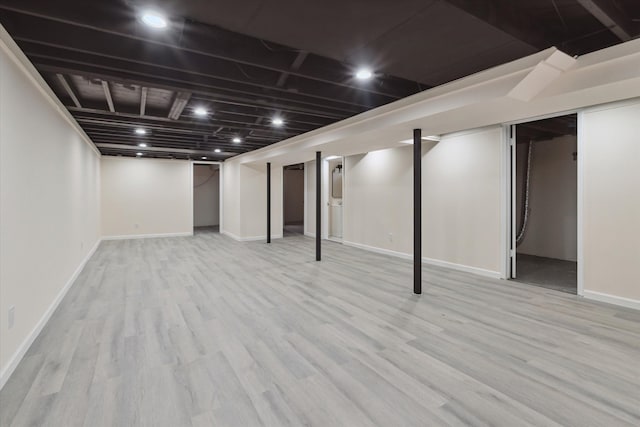 finished below grade area with baseboards and light wood finished floors