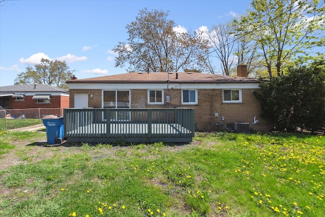 back of house with fence, a deck, a chimney, brick siding, and a yard