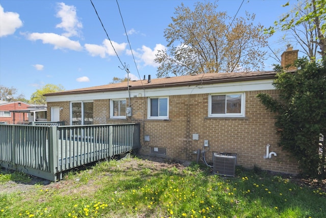 rear view of house with a wooden deck, central AC unit, and brick siding