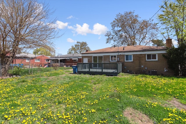 back of house with fence, a chimney, a yard, and brick siding