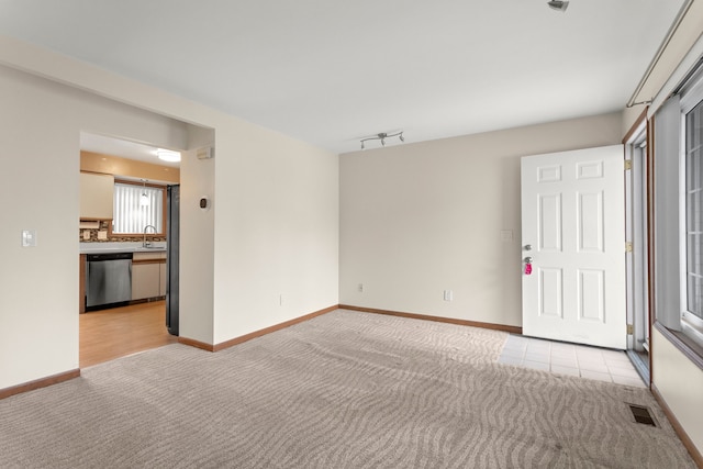 unfurnished room featuring a sink, baseboards, light colored carpet, and visible vents