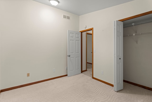 unfurnished bedroom featuring baseboards, light carpet, a closet, and visible vents
