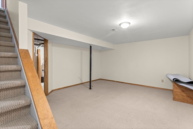 finished below grade area with baseboards, visible vents, light carpet, and stairway