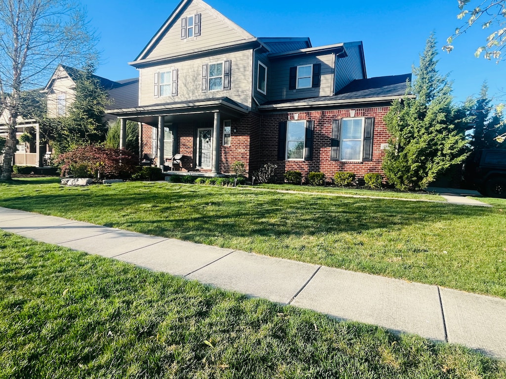 view of front of house featuring a front yard, a porch, and brick siding