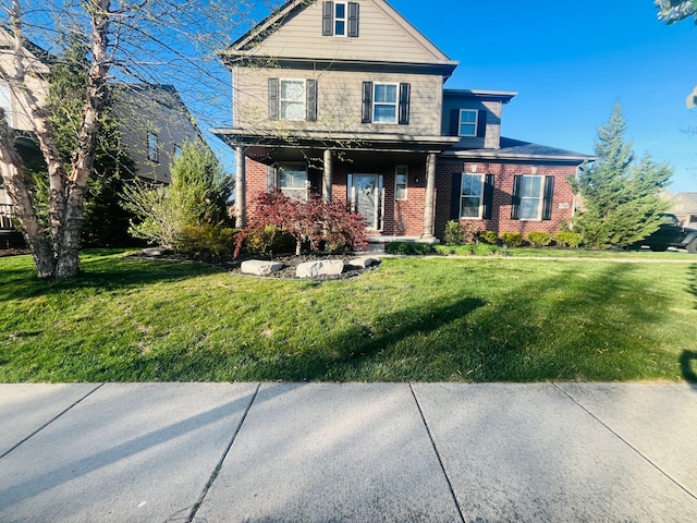 view of front of property with a front yard, a porch, and brick siding