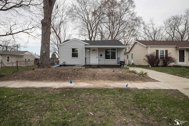 view of front facade featuring fence, covered porch, and a front yard