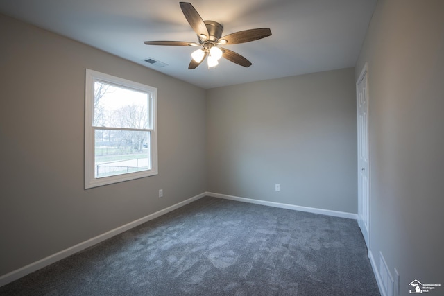 empty room featuring baseboards, a ceiling fan, dark carpet, and visible vents