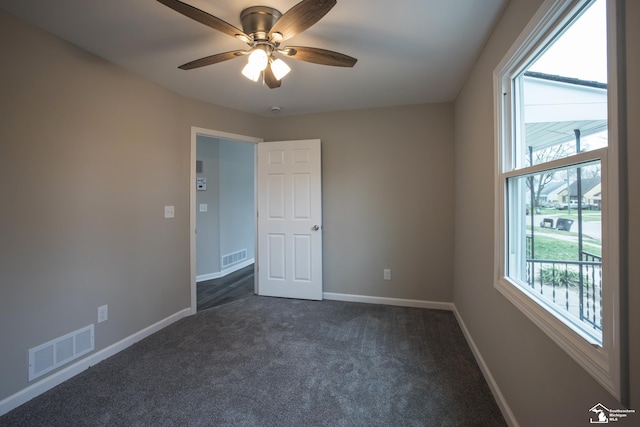 unfurnished room featuring visible vents, a ceiling fan, baseboards, and dark carpet