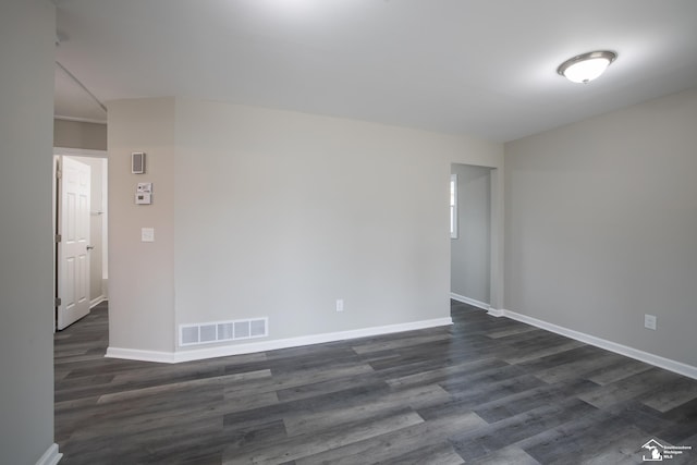 unfurnished room featuring baseboards, visible vents, and dark wood finished floors