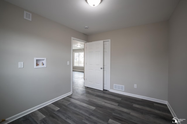unfurnished room featuring visible vents, dark wood-style flooring, and baseboards