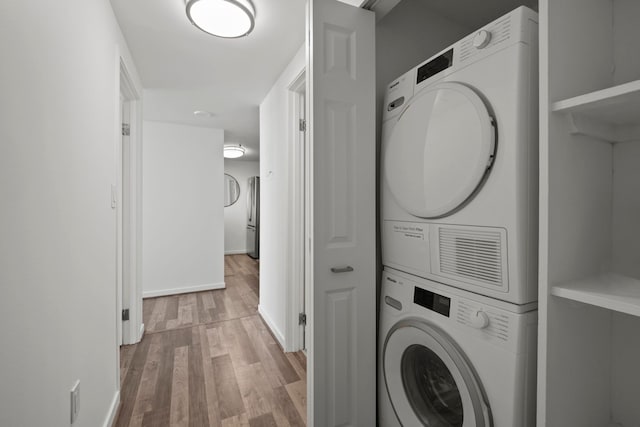 washroom with stacked washer / dryer, light wood-type flooring, and baseboards