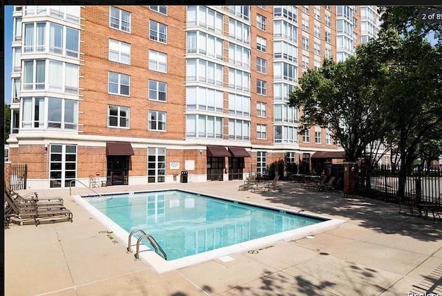 community pool with fence and a patio