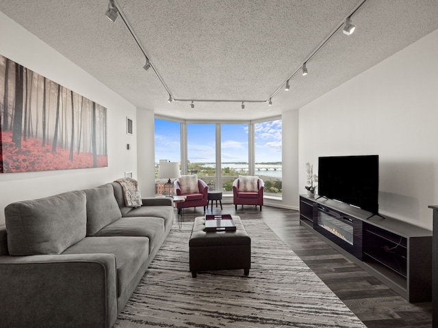 living area with track lighting, dark wood-type flooring, and a textured ceiling