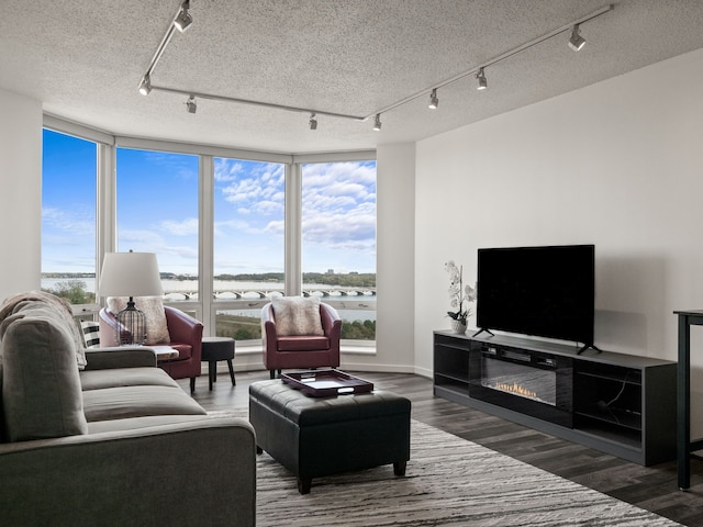 living area featuring track lighting, wood finished floors, a water view, healthy amount of natural light, and a textured ceiling