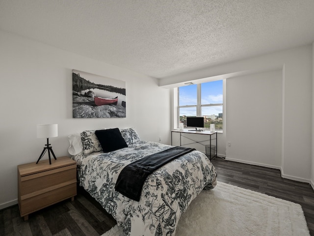 bedroom with dark wood-style flooring, a textured ceiling, and baseboards