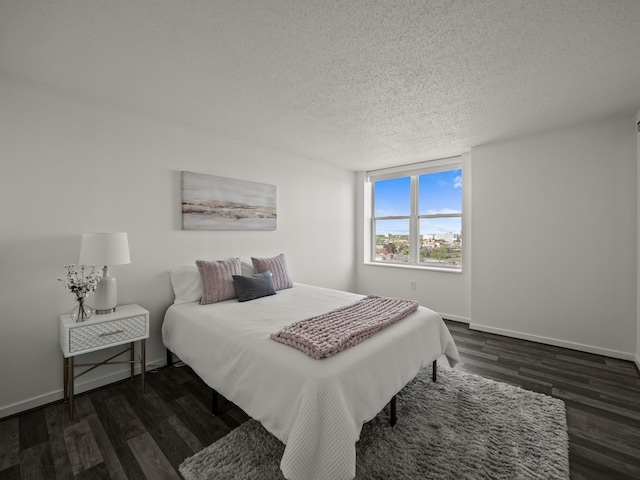 bedroom featuring dark wood finished floors, a textured ceiling, and baseboards
