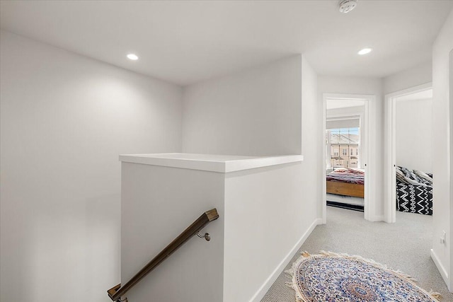 hallway featuring baseboards, carpet, recessed lighting, and an upstairs landing