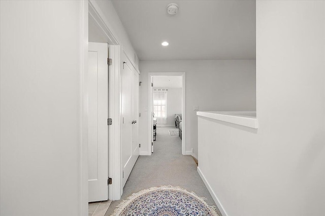 hall featuring baseboards, recessed lighting, and light carpet