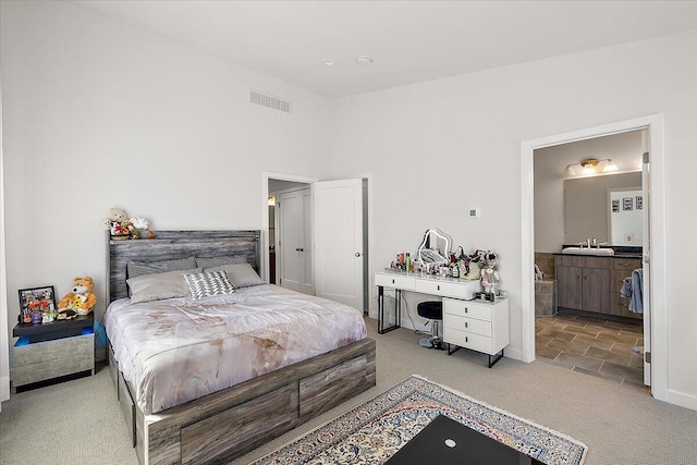 carpeted bedroom featuring a sink, baseboards, and visible vents